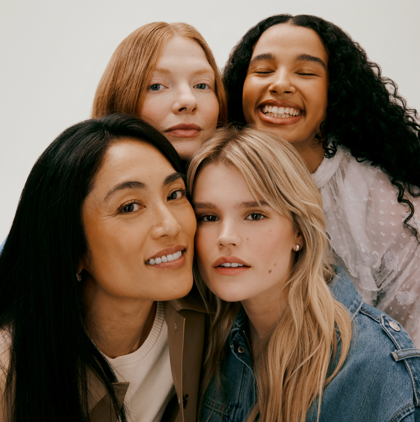 Four women posing together with a plain background